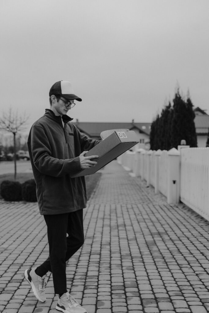 pexels-photo-6169592-6169592 A young male courier carrying a box during a delivery in a residential area.
